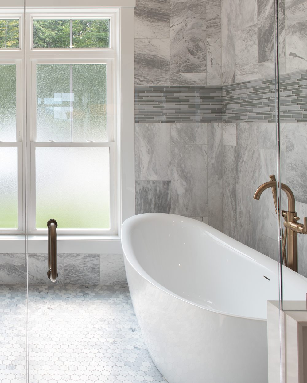 Primary bath with freestanding tub, marble tile and brass fixtures — Candlelight Road project