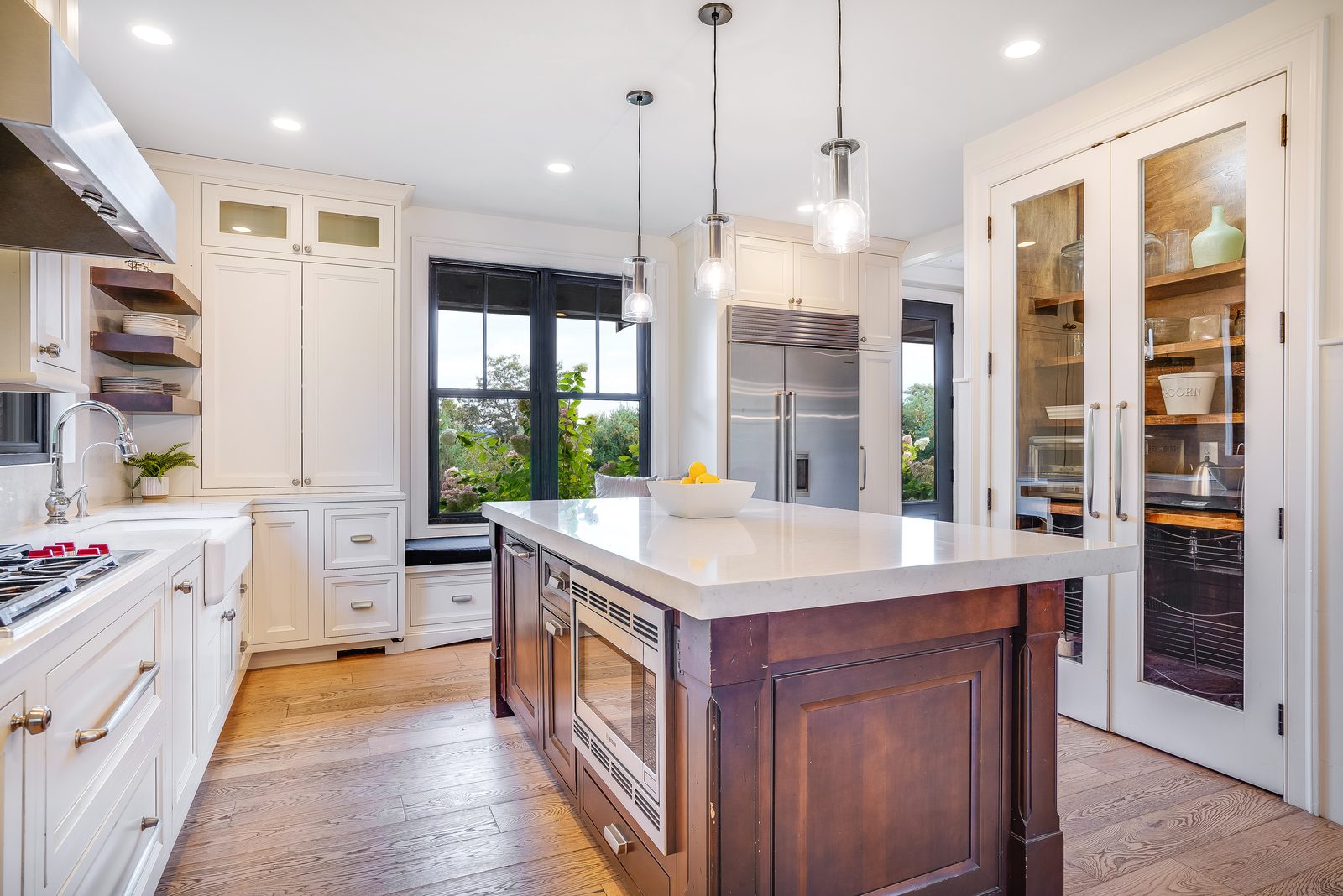 Range wall, stained island and tall glass pantry