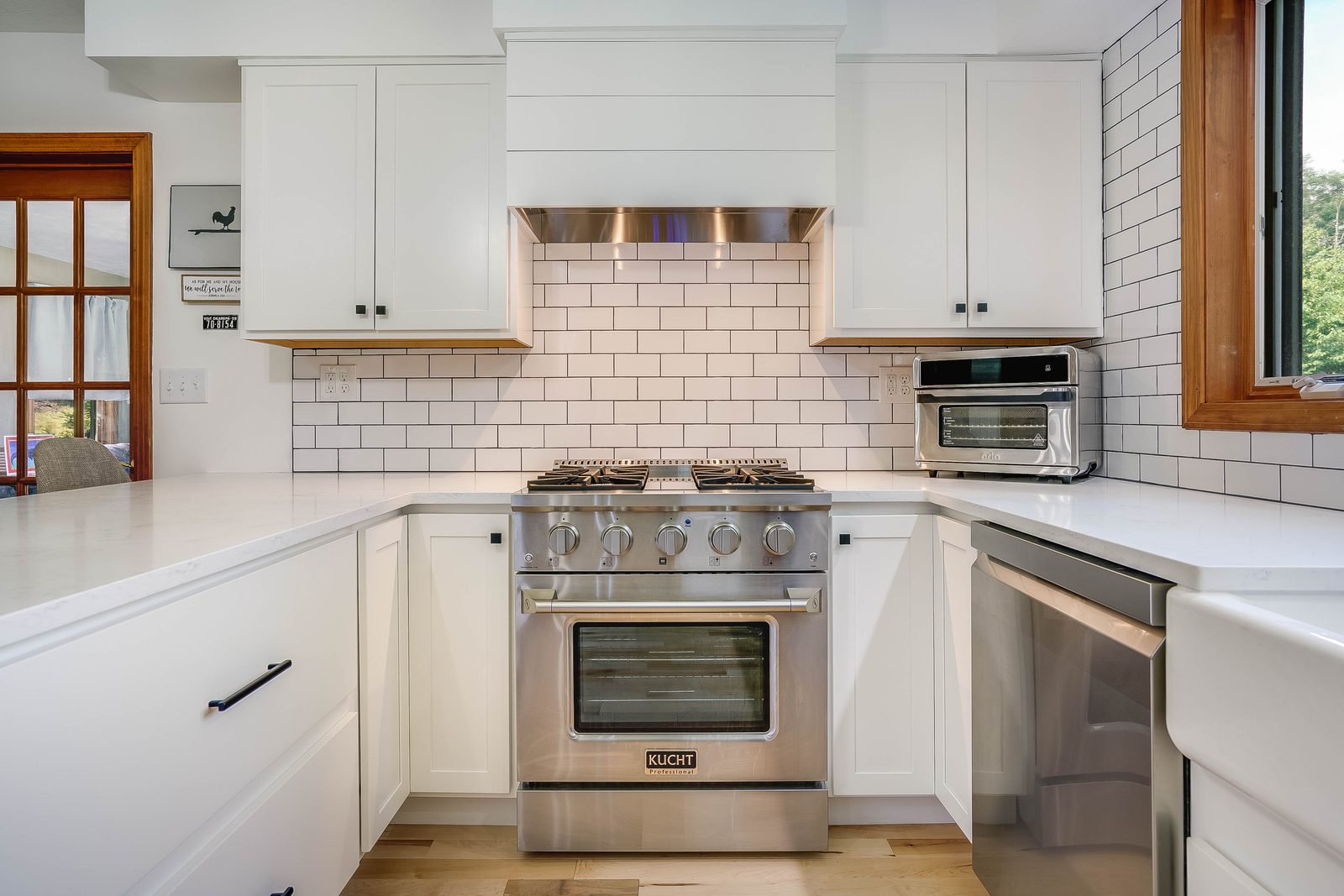 Pro-style range flanked by white cabinetry and subway tile