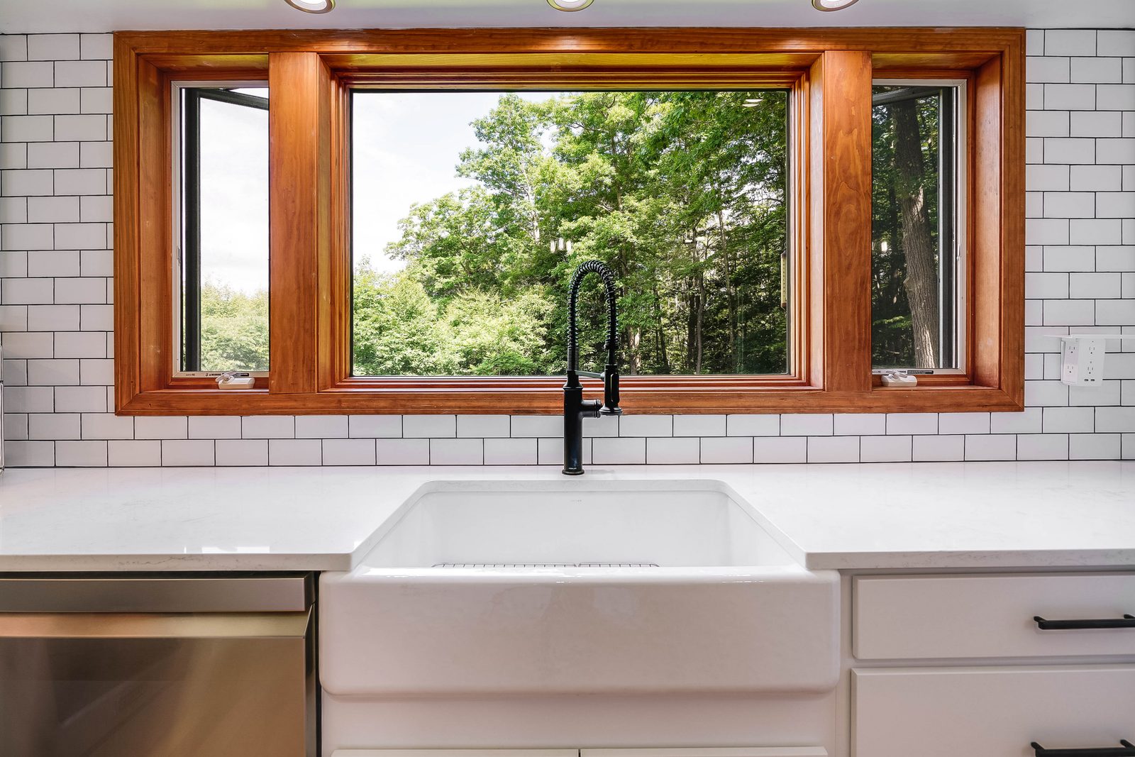 Farmhouse sink under a wood-trimmed picture window