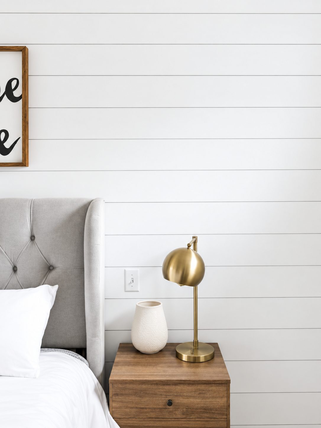 Shiplap bedroom wall with brass lamp and nightstand
