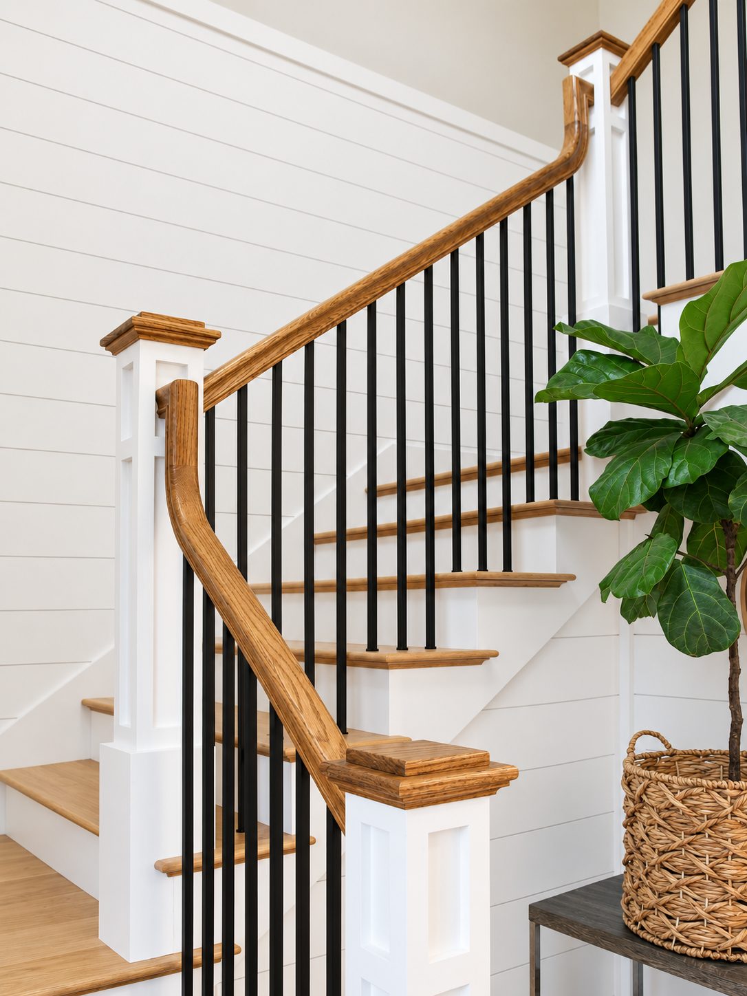Oak staircase with iron balusters against shiplap walls