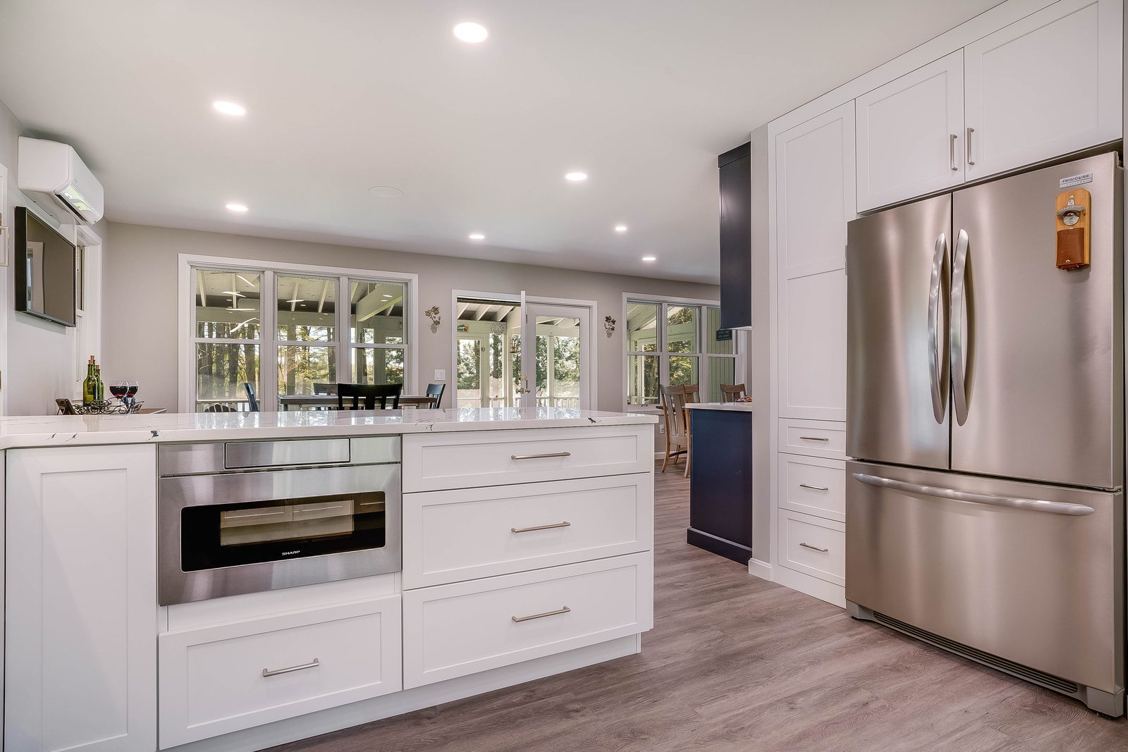 Kitchen opening to the sunroom with paneled fridge run