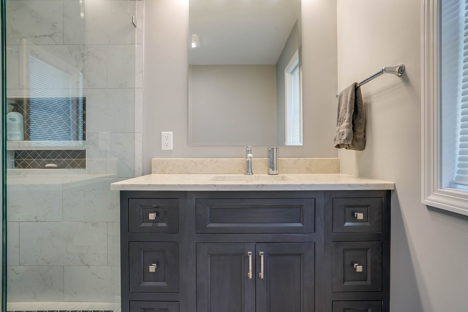 Stained vanity and marble shower in the primary bath