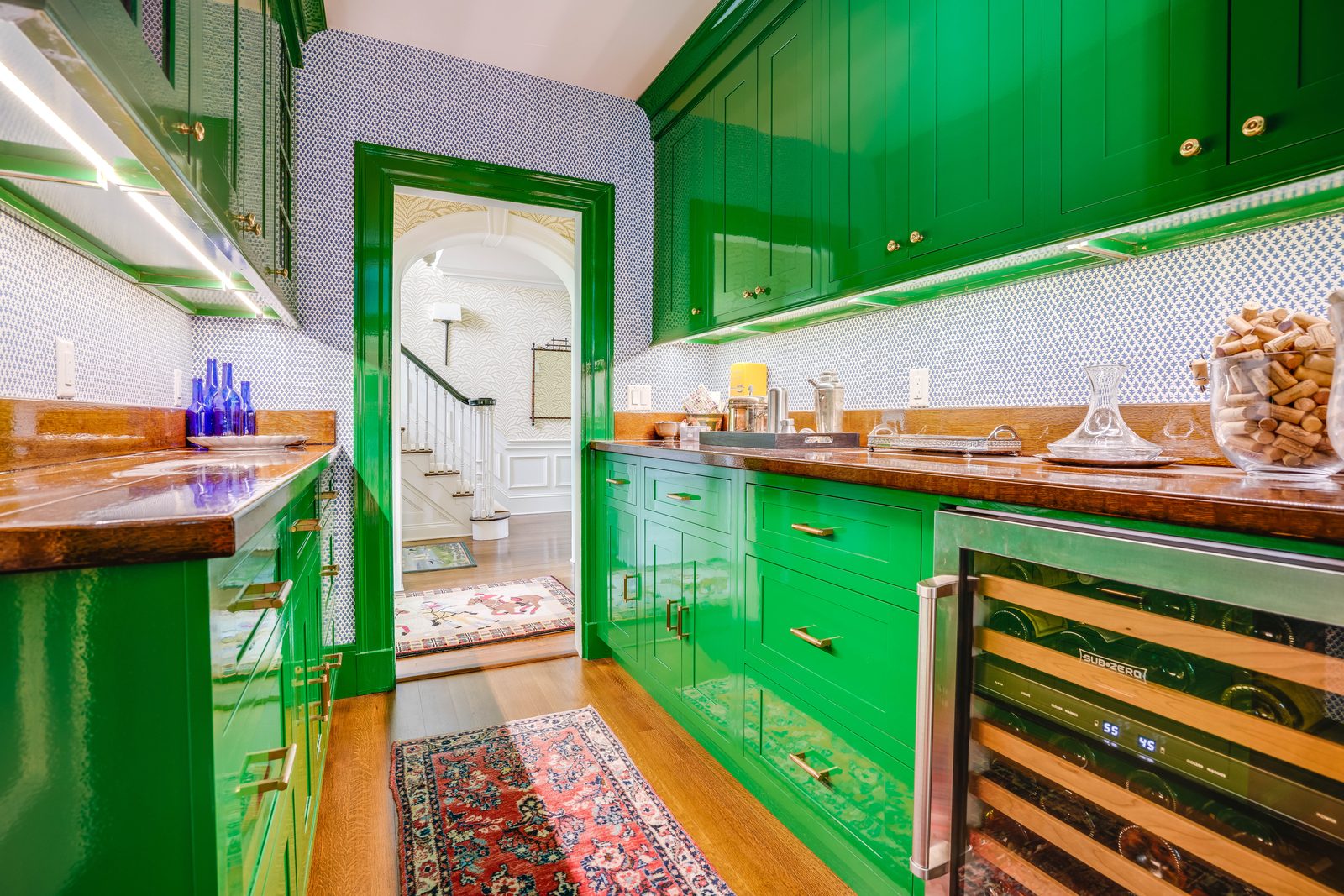 Green pantry cabinetry with wine fridge and warm metal counter