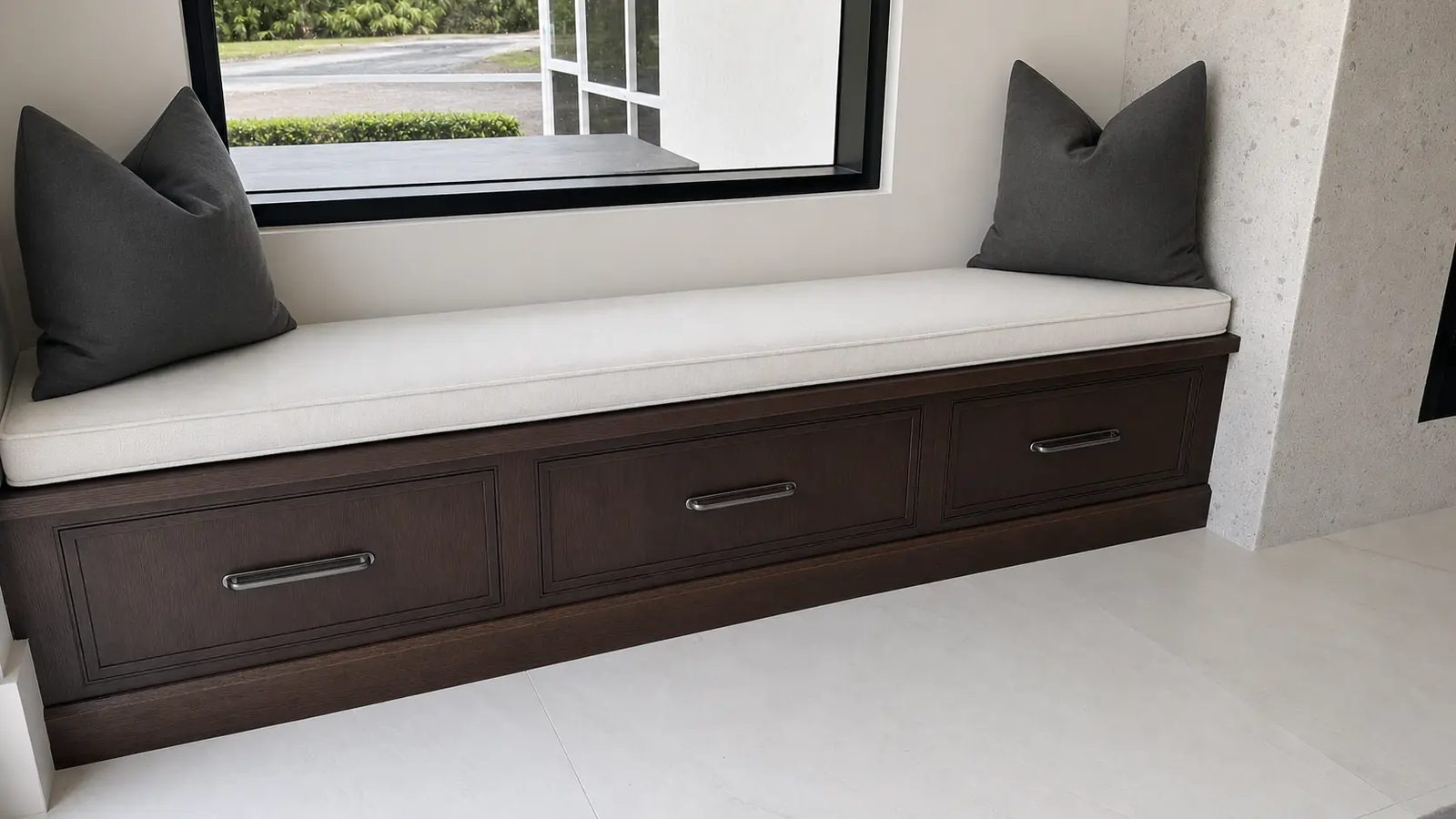 Three-drawer window seat bench in dark oak with cushion and pillows
