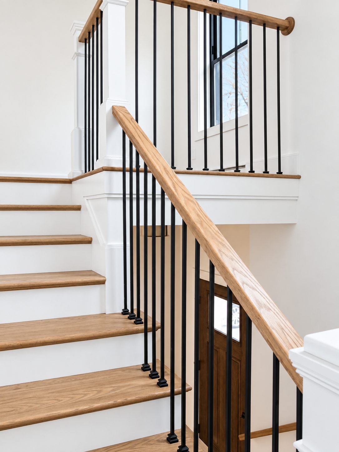 Staircase with oak treads and iron balusters above the entry
