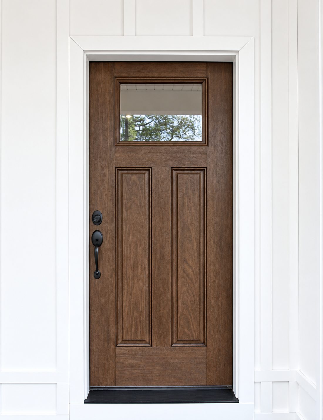Stained craftsman front door with black hardware in a white board-and-batten entry