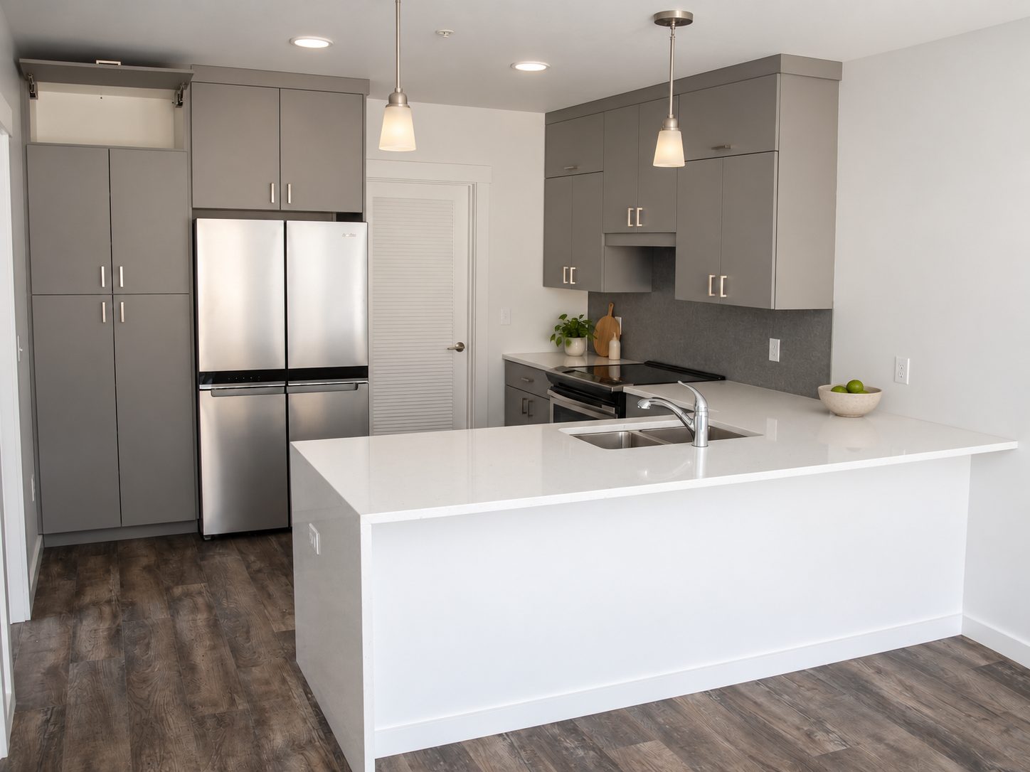 Unit kitchen with pantry cabinets, stainless fridge and pendants