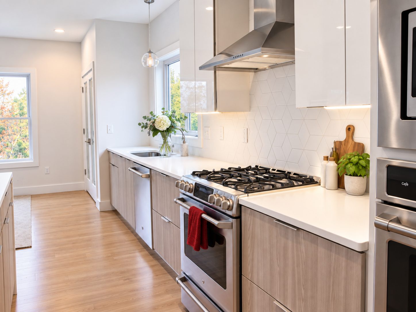 White slab kitchen run with gas range, hood and woodgrain accents
