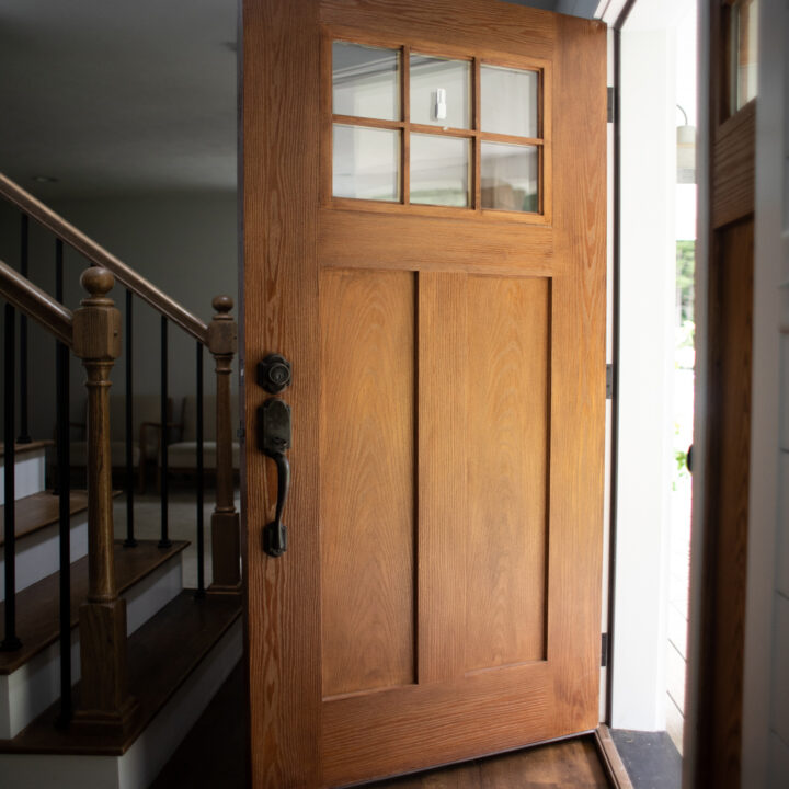 brown wood front door with windows at the top, open into the house